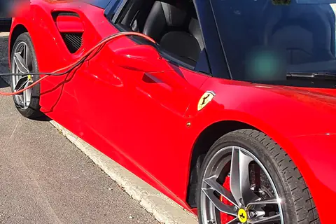 Batería del coche descargada: cables de arranque conectados a un deportivo rojo