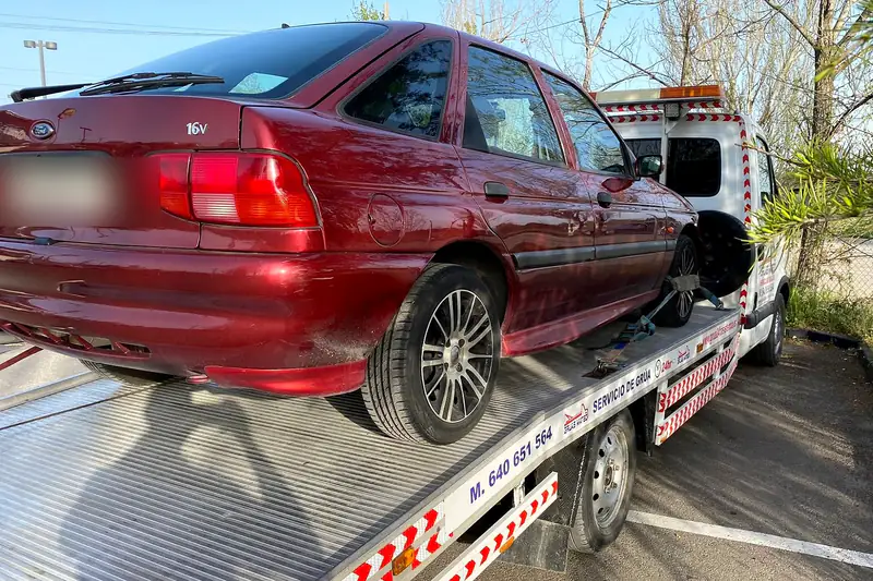Coche antiguo granate cargado en la plataforma de la grúa