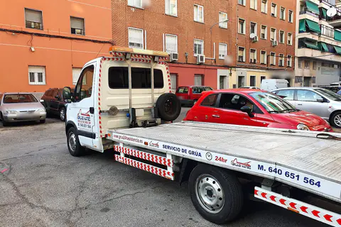 Grúa particular de plataforma en una calle de barrio con edificios de ladrillo
