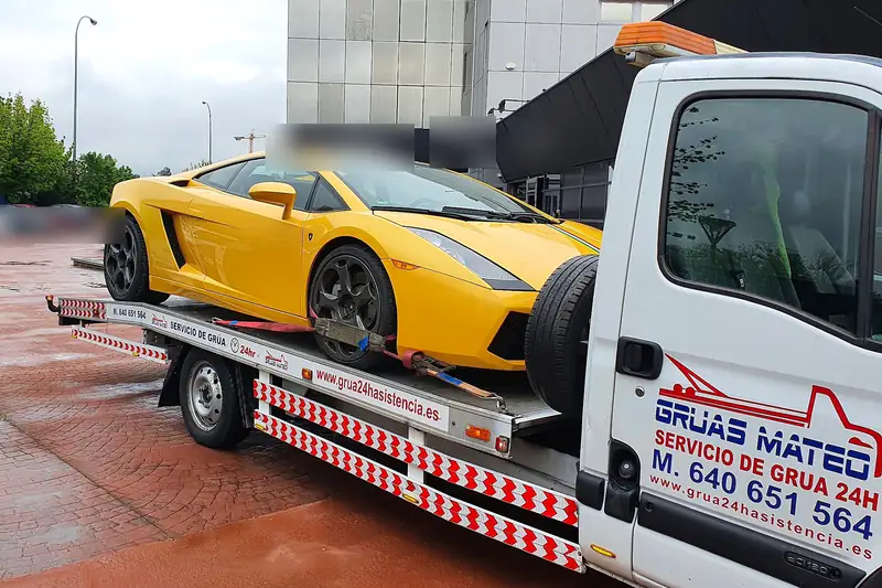 Servicio de grúa con un Lamborghini amarillo cargado en la plataforma junto a un edificio de oficinas